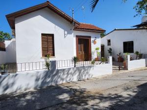 a white house with a brown door on a street at Mystic Guest House Famagusta in Famagusta