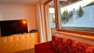 a living room with a television and a window at Adventure Panorama "Salober" Top 9 in Warth am Arlberg