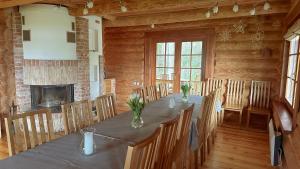 uma sala de jantar com uma mesa longa com cadeiras e uma lareira em Jaunsētas em Alūksne