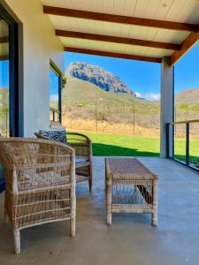 une terrasse couverte avec deux chaises, une table et une montagne dans l'établissement Sneeukop Mountain Cottage, à Paarl