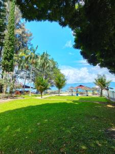 a park with palm trees and the ocean in the background at Hotel Pandu Lakeside Tuktuk in Tuk Tuk