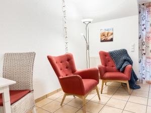 two red chairs and a lamp in a room at FeWo StrandDomicil21 in Dahme