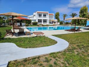 塞奥洛戈斯Ayit Hotel的房子旁边有带椅子和遮阳伞的游泳池