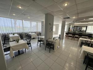 un ristorante con tavoli e sedie bianchi e un pianoforte di Ayit Hotel a Theologos