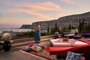una mujer parada en una sala de estar con vistas al océano en Aquagrand Exclusive Deluxe Resort Lindos - Adults only, en Lindos