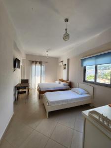 ein großes Schlafzimmer mit 2 Betten und einem Tisch in der Unterkunft Bill's Apartments in Sarandë