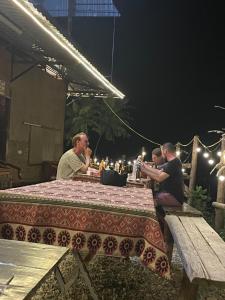 Bao Lac Homestay Hostel & Coffee في Bảo Lạc: مجموعة من الناس يجلسون على طاولة في الليل