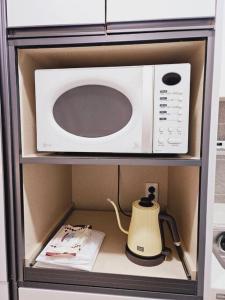 a microwave oven with a tea kettle in a cabinet at Cozy spacious house in Seoul