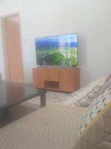 sala de estar con TV de pantalla plana y cama en Appartement vu sur mer, en Kolea