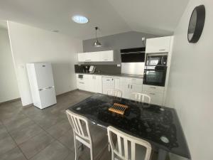 une cuisine avec une table noire et des appareils électroménagers blancs dans l'établissement Maison 47 m2 Biscarrosse proche lac et océan, à Biscarrosse
