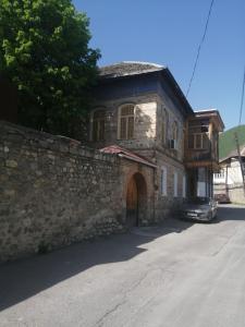 ein Steingebäude mit einem davor geparkt in der Unterkunft Ali Ancient House 555 in Şəki