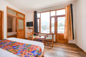a bedroom with a bed and a desk and a window at WooibHotels The Kanchanikoot Manali in Manāli