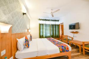 a bedroom with a bed and a table and a television at WooibHotels The Kanchanikoot Manali in Manāli