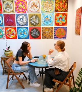 dos mujeres sentadas en una mesa frente a una pared en B&B Ibla Art Centro, en Ragusa