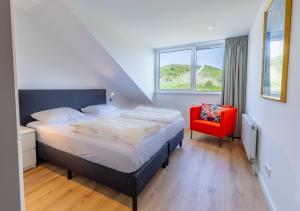 um quarto com uma cama e uma cadeira vermelha em Hogehilweg 16 vakantiehuis, Direct onder de duinen - eigen parkeerplaatsen em Domburg