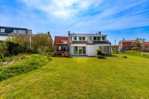 uma casa com um grande relvado em frente em Hogehilweg 16 vakantiehuis, Direct onder de duinen - eigen parkeerplaatsen em Domburg