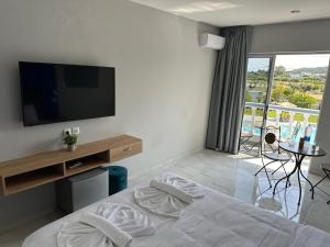 a bedroom with a bed with a television and a balcony at Ayit Hotel in Theologos