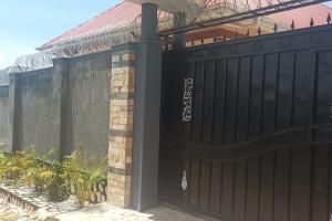 a black fence with a gate in front of a house at Home Waka in Wakiso