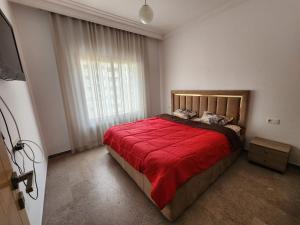 a bedroom with a large bed with a red blanket at Luxury in Sidi Daoud
