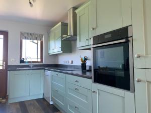 una cucina con mobili bianchi e un microonde nero di Relaxing Retreat on the Stunning Ards Peninsular a Millisle