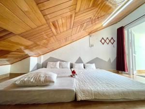 大叻的住宿－WINTERFEll HOTEL，一间卧室设有一张带木制天花板的大床