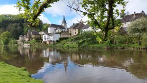 een rivier voor een groep huizen bij Chez Rosé in Sainte-Cécile