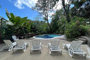 a group of lawn chairs and a swimming pool at 2BR Eco Condo 1 AC 5MINS to Medical Center in Quepos