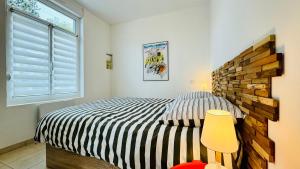 a bedroom with a striped bed and a window at La scintillante au coeur de Merlimont Plage in Merlimont