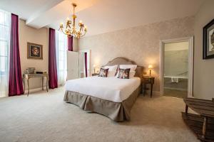 Un dormitorio con una gran cama blanca y una lámpara de araña. en Hôtel de la Poste, en Avallon