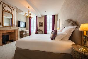 um quarto com uma grande cama branca e uma lareira em Hôtel de la Poste em Avallon