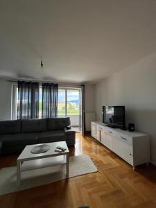 een woonkamer met een bank en een tv bij Waves Apartment 106 in Sarajevo
