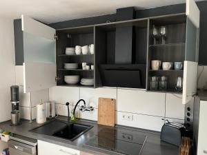 a kitchen with black and white cabinets and a sink at Ferienwohnung Voerde-Götterswickerhamm-"die Perle am Niederrhein" in Götterswickerhamm +8 photos