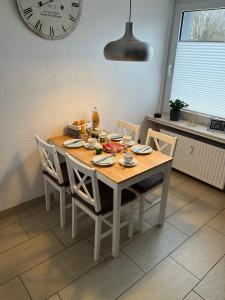 mesa de comedor con sillas y reloj en la pared en Ferienwohnung Voerde-Götterswickerhamm-"die Perle am Niederrhein" en Götterswickerhamm