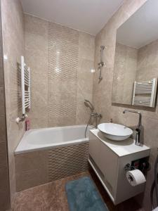 een badkamer met een bad, een wastafel en een spiegel bij Waves Apartment 106 in Sarajevo