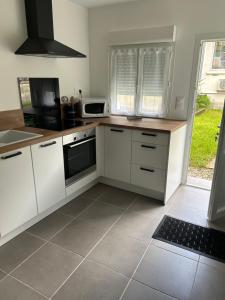 a kitchen with white cabinets and a tile floor at Maison de ville au coeur de Ribérac in Ribérac