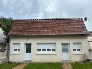 een wit huis met twee ramen en een dak bij Maison de ville au coeur de Ribérac in Ribérac