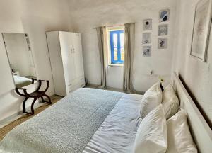 a bedroom with a bed with white sheets and a window at Villa Kotseli - Sea View, Pool, Sunsets in Andros