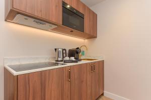 uma cozinha com armários de madeira e um micro-ondas em Novallure Villa Margaretha - Short Stay Apartments em Rijswijk
