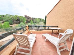 uma varanda com 2 cadeiras, uma mesa e uma mesa em La perle du Roussillon em Fitou