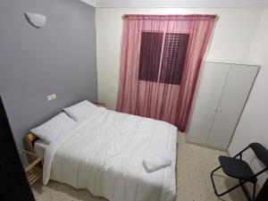 1 dormitorio con cama blanca y cortina rosa en perfect place in Casa but not too close, great transportation and 5km to the beach and shops all around trams, buses, train, en Casablanca