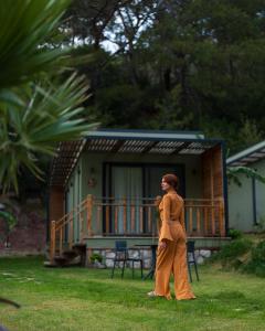 a woman walking in the grass in front of a house at Sea Valley Lodge in Faralya