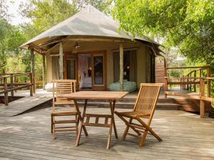 une table et des chaises en bois sur une terrasse avec une tente dans l'établissement Muzimu Lodge, 