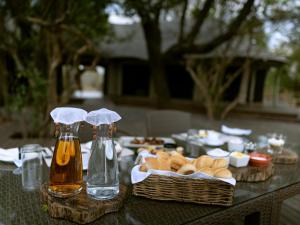- une table avec des bouteilles de bière et un panier de pain dans l'établissement Muzimu Lodge, 