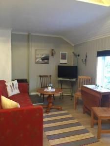 a living room with a red couch and a piano at Sjøstrand Rorbuer v Børge Iversen AS in Ballstad