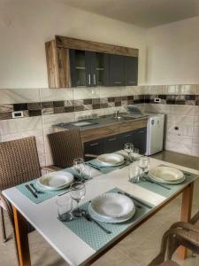 einen Tisch mit Tellern und Gläsern darauf in der Küche in der Unterkunft Apartman Cvetkovic in Vranje