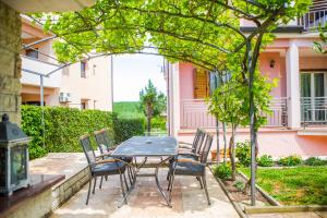 a patio with a table and chairs under a tree at Apartments Lorena in Poreč