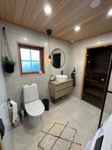 een badkamer met een toilet, een wastafel en een spiegel bij Upea villa lähellä rantaa poreallas & SUP-laudat in Vaasa