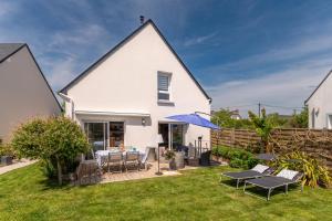 une maison blanche avec un patio et une pelouse dans l'établissement Belle maison de vacances, à Belz