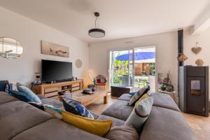 un salon avec un canapé et une télévision dans l'établissement Belle maison de vacances, à Belz