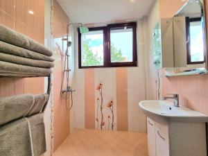 a bathroom with a sink and a shower with a window at Comfortable Family Apartment with Parking in Burgas
